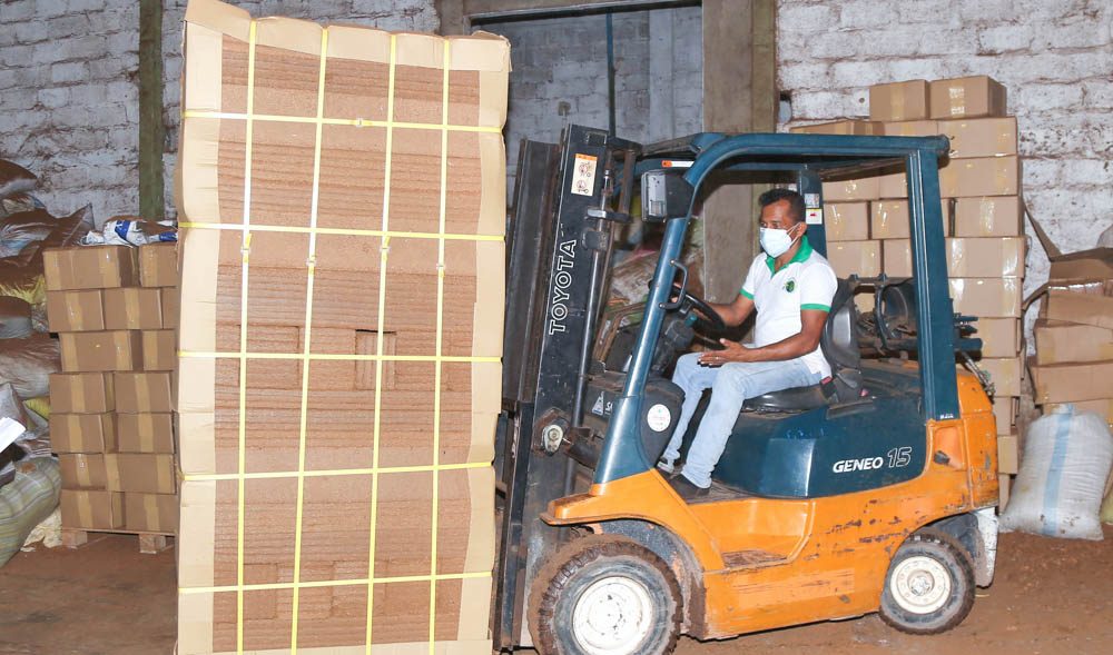 A forklift carrying a strapped pallet of coco peat blocks through a finished-goods store