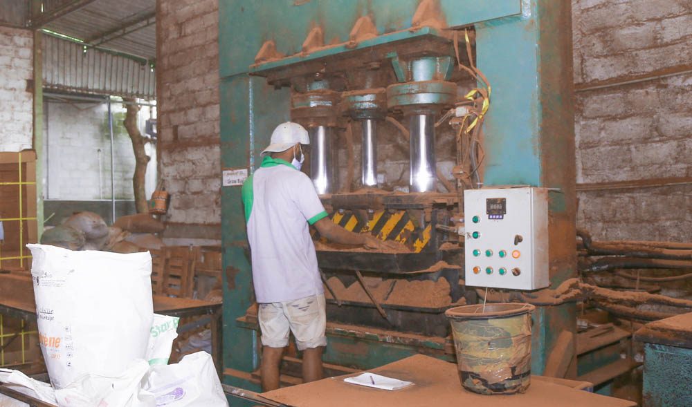 An operator working a hydraulic block press on the factory floor